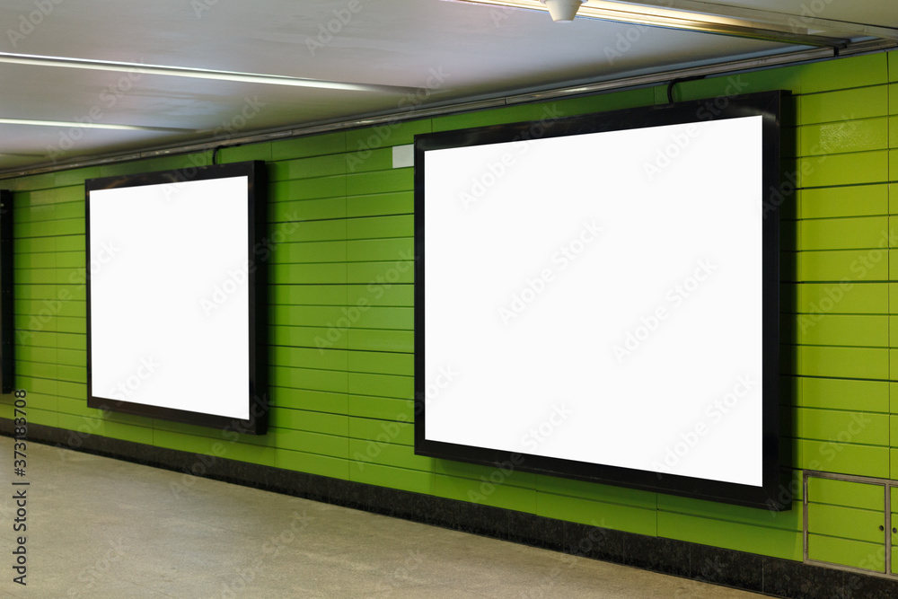 Two horizontal billboards on a green wall in an underground passage. Two horizontal billboards on a green wall in an underground passage.