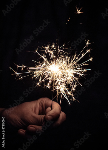 hand with sparkler on black background 