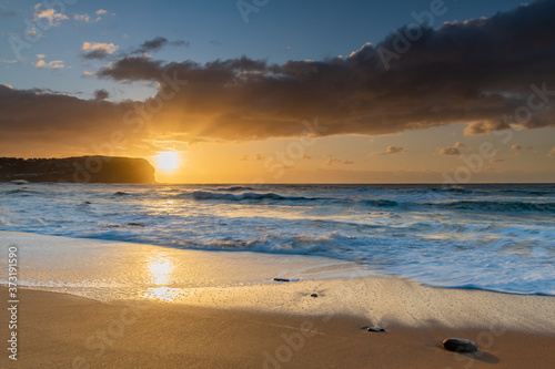 Sunrise at the beach with waves and clouds