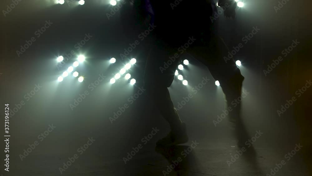Silhouette of a talented young break dancer. Hip hop street dance on a stage in front of the spotlight. Legs close up.