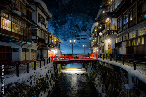 Illumination of Light at Ginzan Onsen with Snow falling in Winter Night, photo