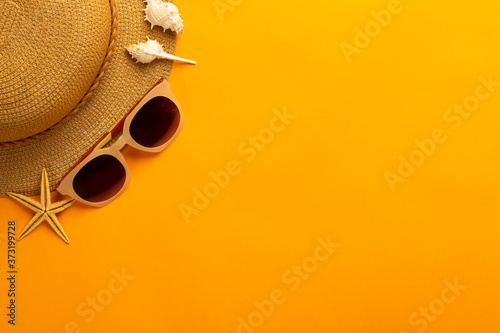 Summer background with beach accessories - straw hat, sunglasses on vibrant orange background top view with copy space. © Touchr