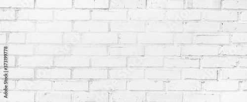 Light white black and gray horizontal brick wall. Old uneven textured surface on a building in the city. Urban background in grayscale. White painted bricks.