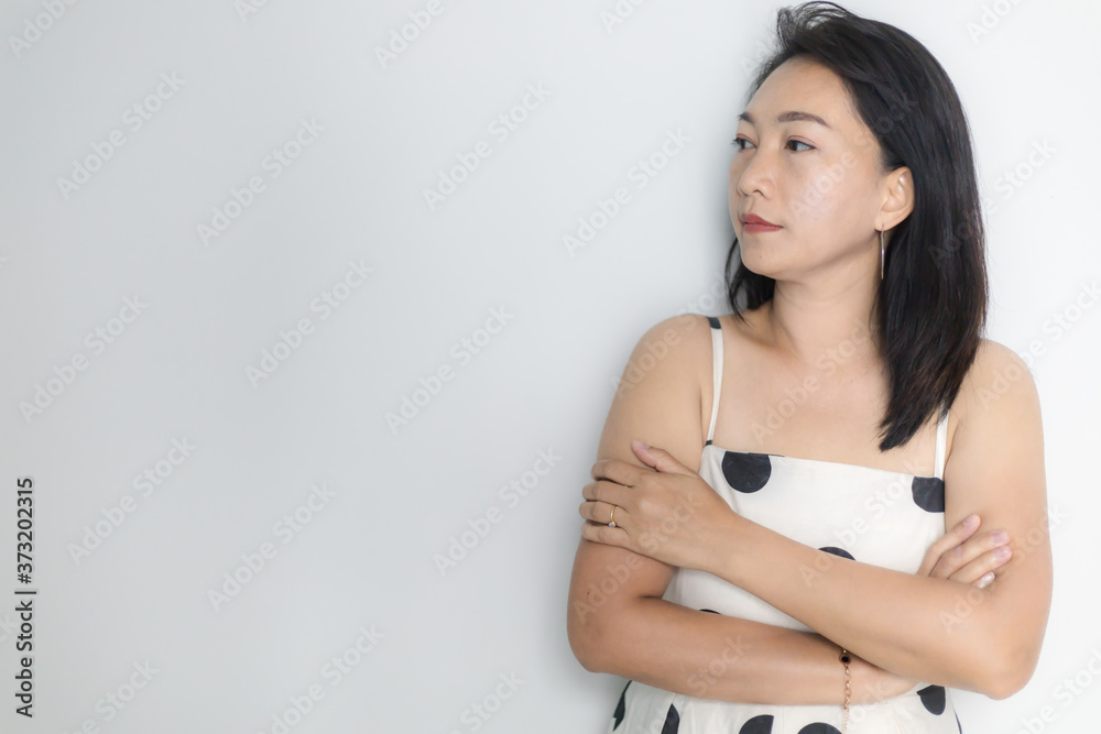 Portrait of beautiful adult (40 years old) Asian woman in polka dots dress with arms crossed and pretending straight face over isolated white background. Portrait of beautiful adult (40 years old) Asian woman in polka dots dress with arms crossed and pretending straight face over isolated white background.