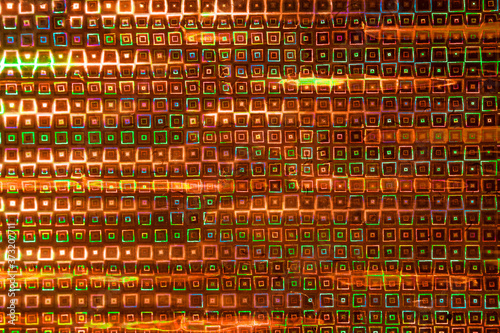 Photo of a multi-colored texture and background. Geometric repeating shapes in orange and green tones.