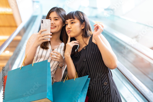 Happy asian woman with shopping bags enjoying in shopping.lifestyle concept.Smiling girl  holding colour paper bag.Friends walking in shopping mall.time shopping .