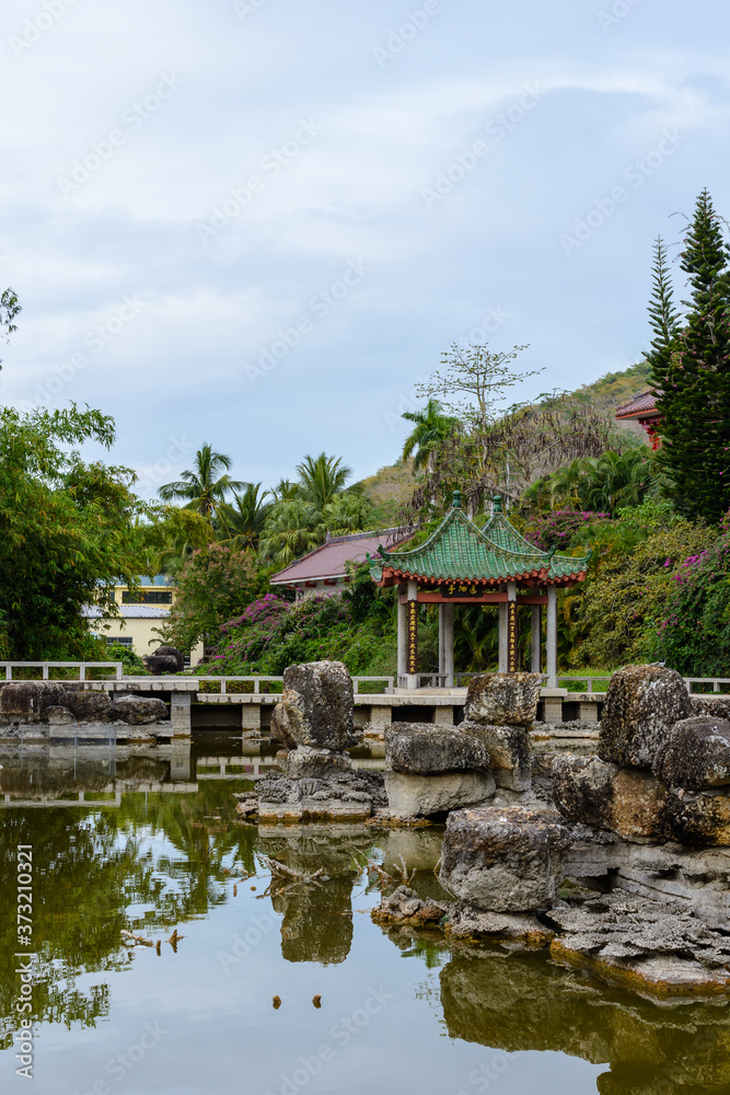 Green lake surrounded by gazebos, temples, mountains, flowers, palm grove and stone fence on the territory of Buddhist center Nanshan. Green lake surrounded by gazebos, temples, mountains, flowers, palm grove and stone fence on the territory of Buddhist center Nanshan.
