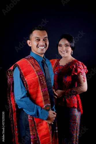 portrait of beautiful indonesian couple wearing traditional batak costume isolated on black background. photo