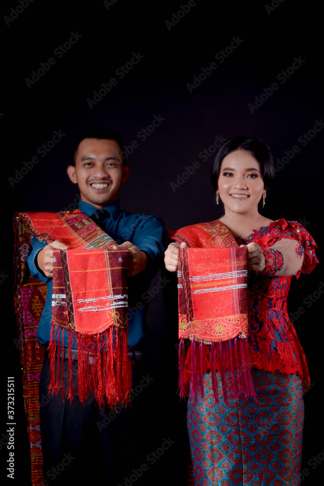 portrait of beautiful indonesian couple wearing traditional batak costume isolated on black background.