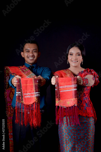 portrait of beautiful indonesian couple wearing traditional batak costume isolated on black background.