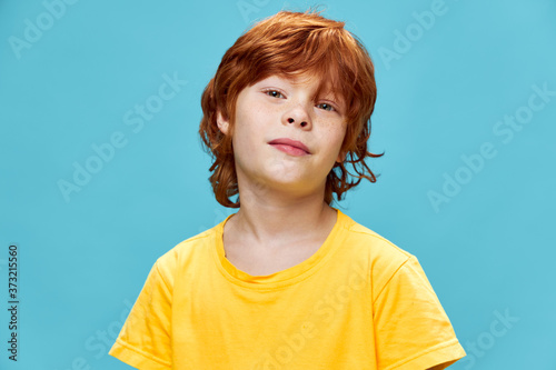 Red-haired boy in a yellow T-shirt on a blue background 