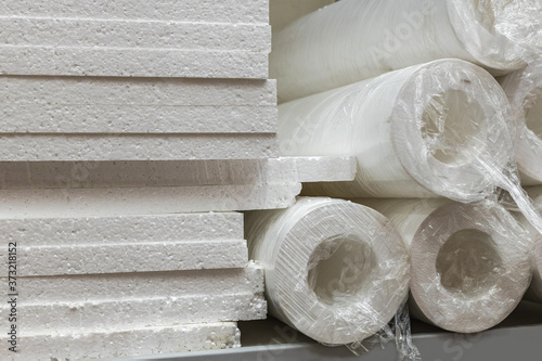 Stacks of expanded polystyrene sheets and in the form of pipes in packaging at a building materials warehouse in a store. The insulation is in the distribution warehouse.