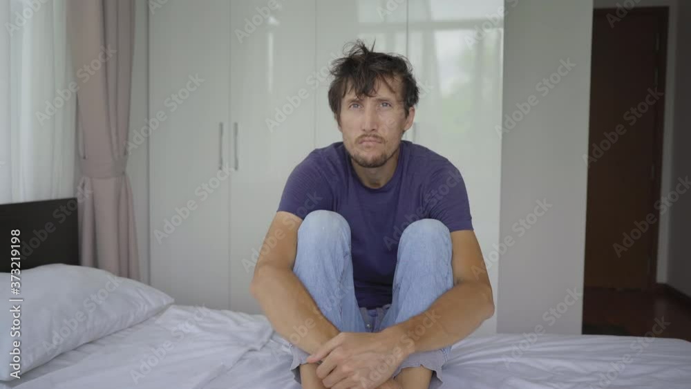 A young man in mandatory quarantine. He stays in one room for two weeks. He did not shave for a long time, he is stressed and upset. Staying in quarantine concept. Concept of the second wave of Covid A young man in mandatory quarantine. He stays in one room for two weeks. He did not shave for a long time, he is stressed and upset. Staying in quarantine concept. Concept of the second wave of Covid