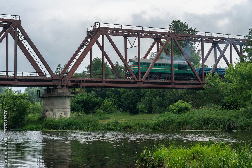 Freight train rides on a railway bridge over the river Freight train rides on a railway bridge over the river