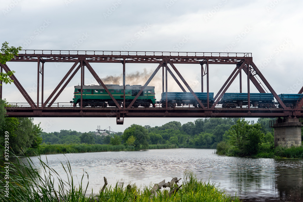 Freight train rides on a railway bridge over the river Freight train rides on a railway bridge over the river