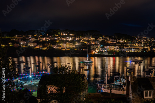 town lit up at night with reflection on water with boats