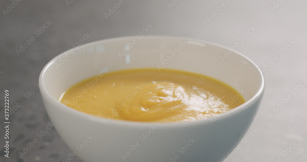 Pumpkin cream soup in white bowl on concrete background Pumpkin cream soup in white bowl on concrete background