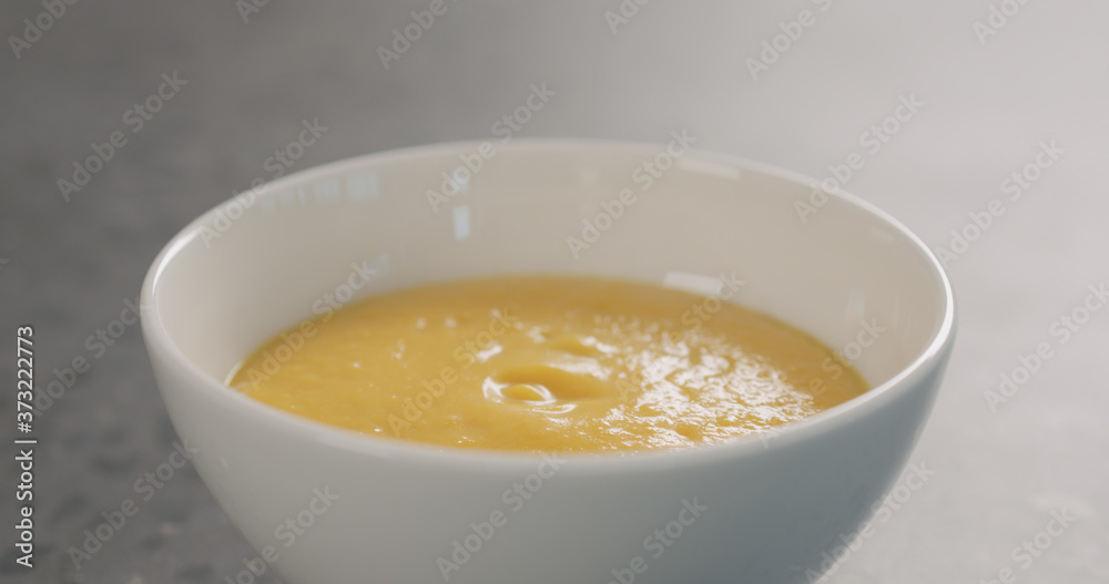 Pumpkin cream soup in white bowl on concrete background Pumpkin cream soup in white bowl on concrete background
