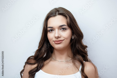 Portrait of a girl with makeup on a white wall. Beautiful girl on a white background. Portrait. Makeup.