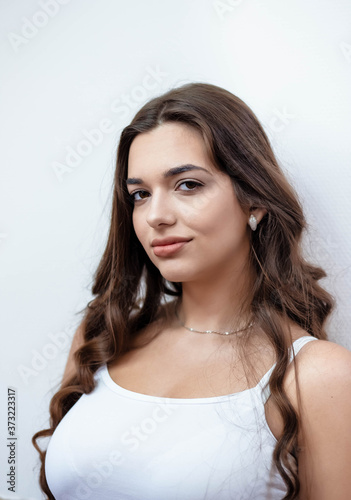 Portrait of a girl with makeup on a white wall. Beautiful girl on a white background. Portrait. Makeup.
