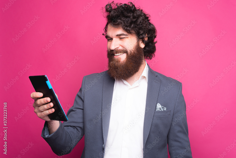 Photo of cheerful man with beard in suit using tablet. Photo of cheerful man with beard in suit using tablet.