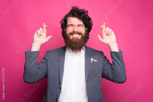 Photo of man in casual crossing fingers over pink bakcgorund. photo