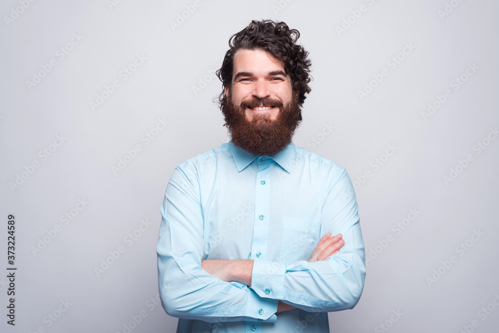 Portrait of happy smiling bearded man in blue shirt with crossed arms looking at the camera. Portrait of happy smiling bearded man in blue shirt with crossed arms looking at the camera.