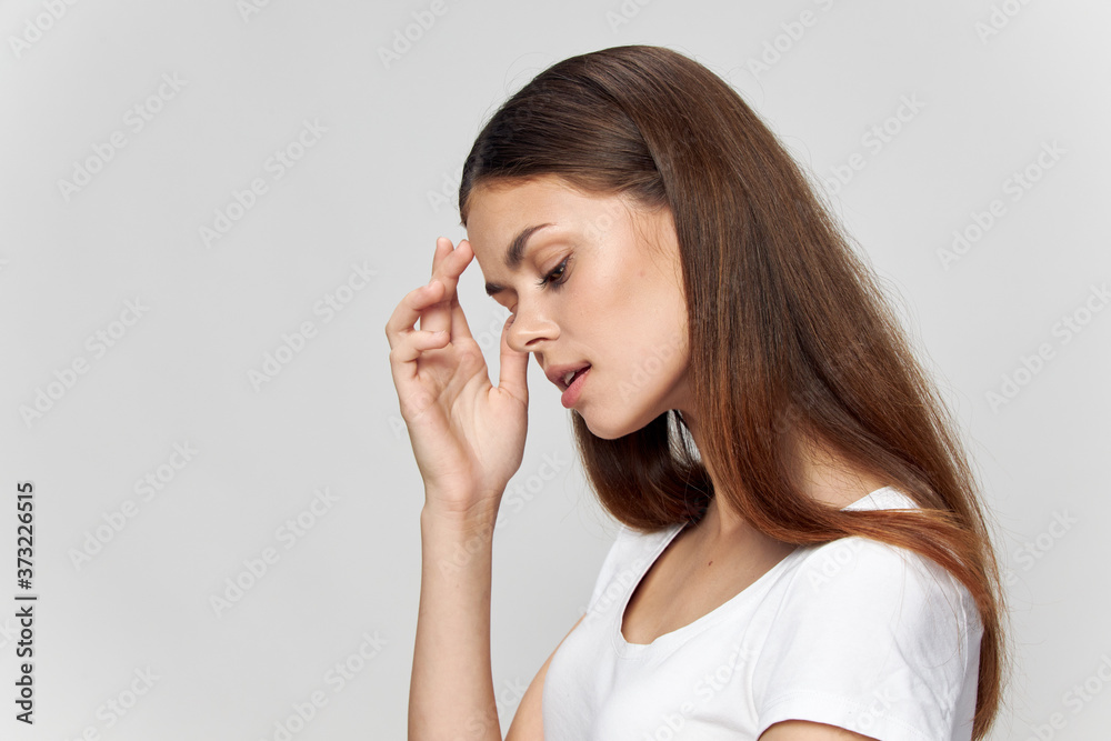 Brunette with closed eyes touches her face with hands, side view Brunette with closed eyes touches her face with hands, side view