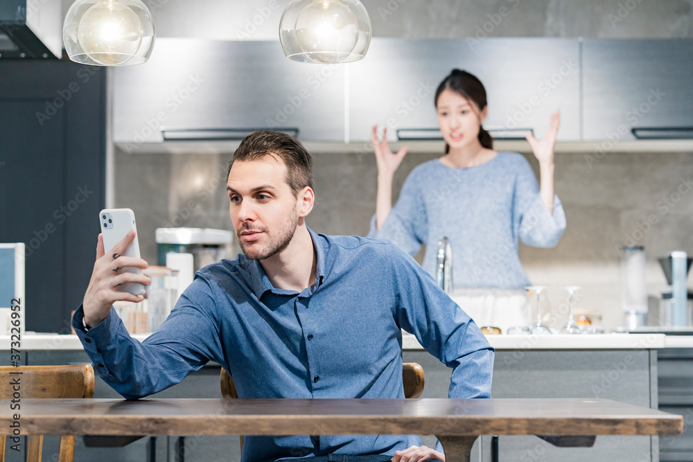 スマートフォンを操作する男性と、怒る女性 スマートフォンを操作する男性と、怒る女性