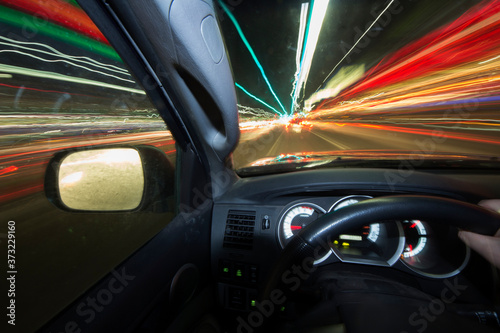 A long exposure photo from inside a car with traffic and lights wooshing by.