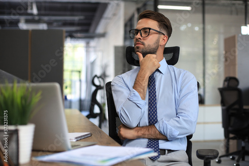 Focused businessman thinking at modern office into report file calculating stock market earnings, startup business.