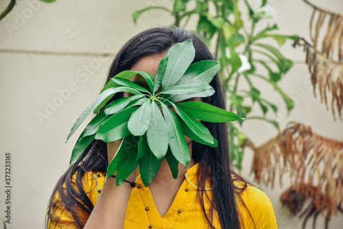 Portrait of young woman holding leaves against face