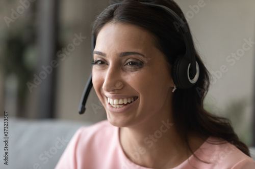 Crop close up of smiling Arabic indian woman in headset consult client customer online, happy young ethnic female in headphones talk speak on video call, have distant virtual event or conference