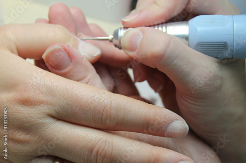 Working moments in the process of hardware and manual classic manicure on the client s female hands by a manicure master