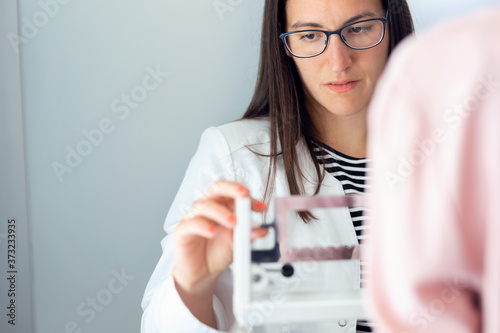 Beautiful young nutritionist woman weighing and measuring his patient on the scale in consultation.