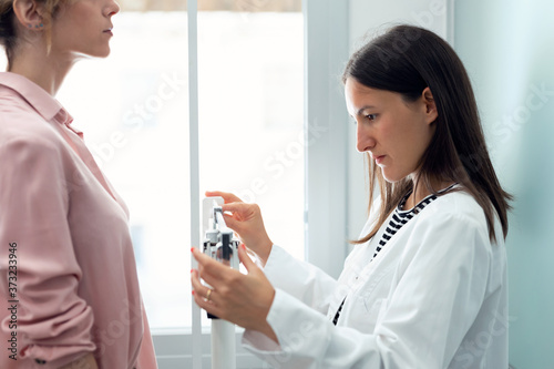 Fototapeta Beautiful young nutritionist woman weighing and measuring his patient on the scale in consultation