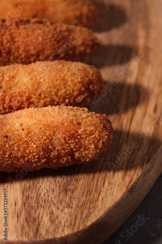 Homemade traditional spanish croquettes on a wood board and black background. Tapas food. Dark food.