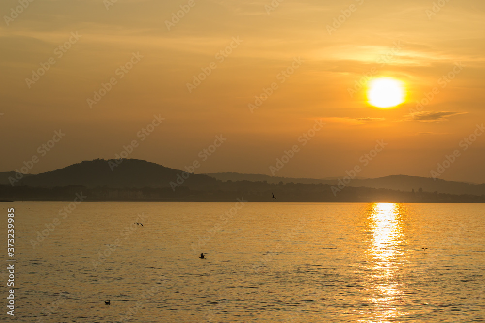Golden hour sunset at Colwyn bay, North Wales. Warm sky with seagulls sitting on the water.