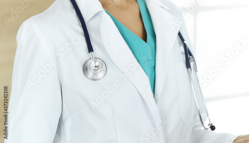 Unknown female doctor sitting and using tablet computer in clinic, close-up. Medicine concept