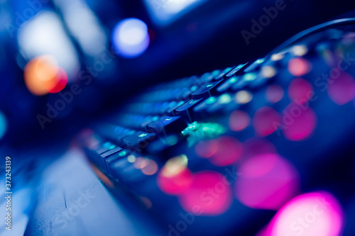 Professional cyber video gamer studio room with personal computer armchair, keyboard for stream in neon color blur background. Soft focus