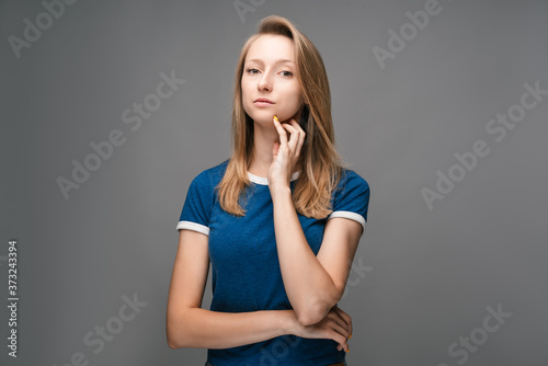 Thoughtful young female looking confident at the camera with hand raised on chin. Concept of thinking
