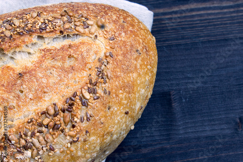 Rye bread with sunflower seeds and flax seeds on a dark wooden background. Fresh bread. Close-up. View from above. Copy space for text.