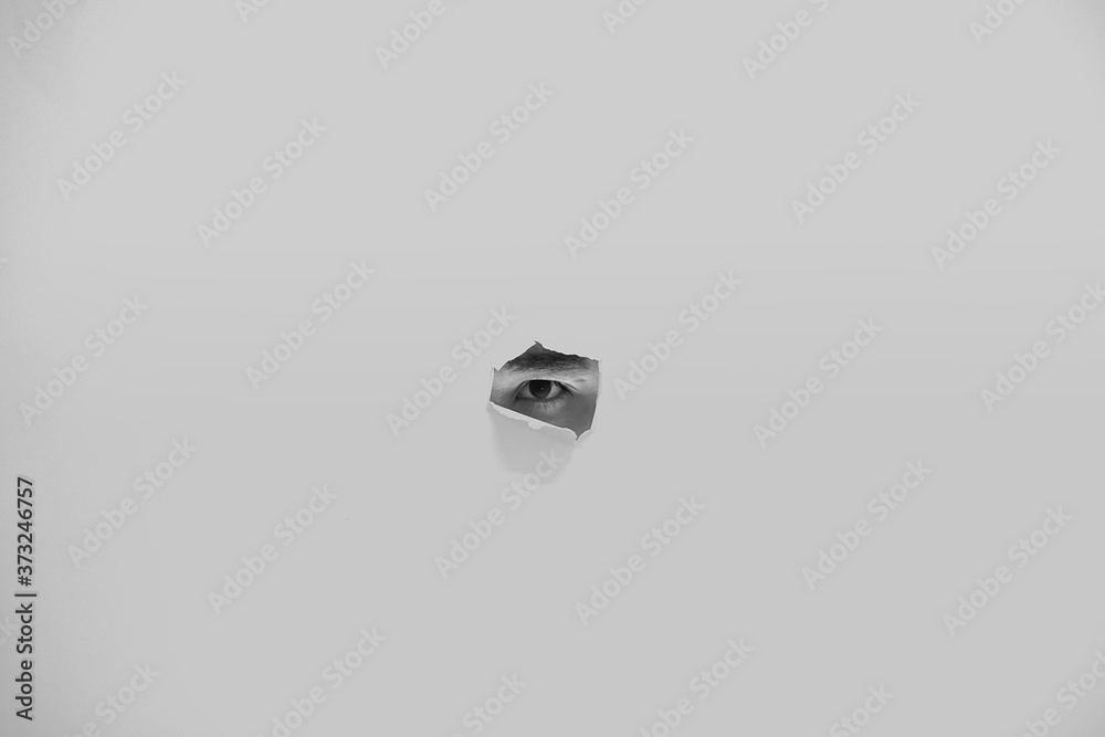 Peeking eye of a man through small hole, with white background. Peeking eye of a man through small hole, with white background.