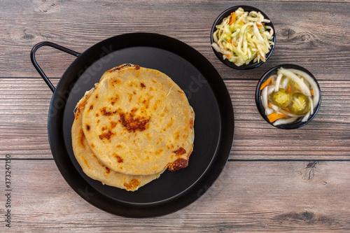 Top  view  of the delicious pupusas  on the pan next to salads in bowls photo