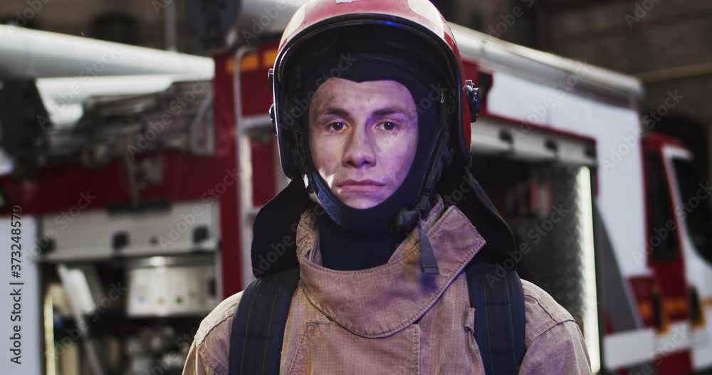 Portrait of caucasian handsome fireman in helmet and gull equipment standing next to the car and looking into camera. The concept of saving lives, heroic profession, fire safety Portrait of caucasian handsome fireman in helmet and gull equipment standing next to the car and looking into camera. The concept of saving lives, heroic profession, fire safety