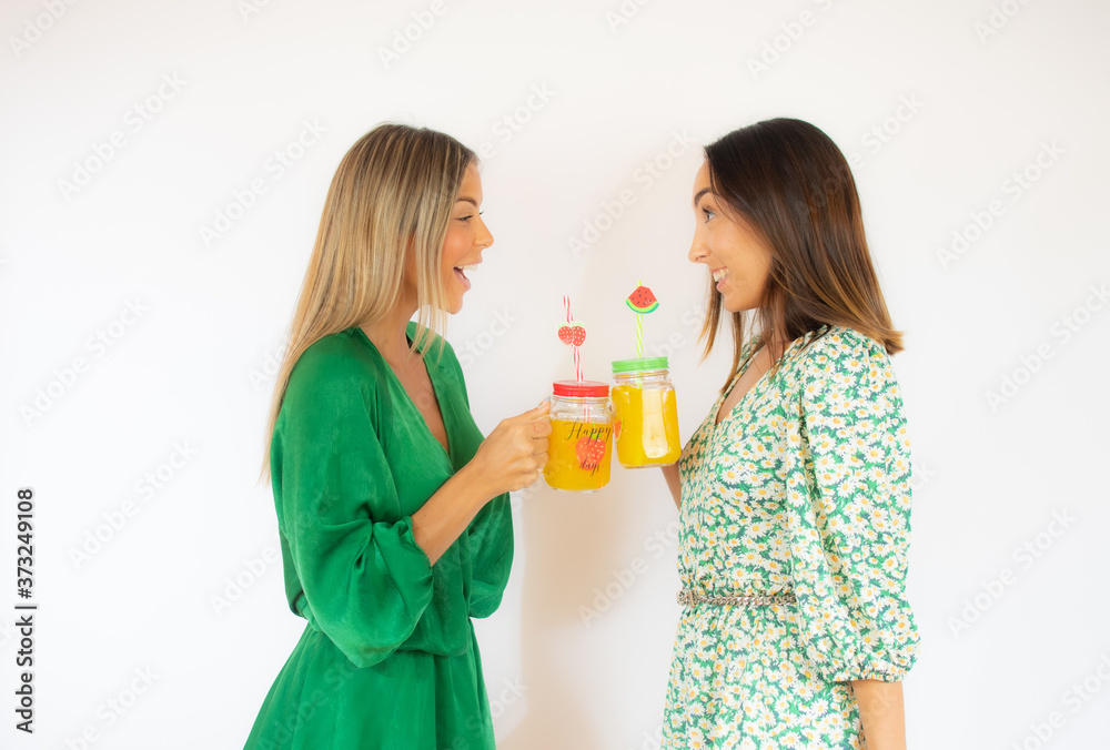 Two friends in green dresses with a cocktail smiling Two friends in green dresses with a cocktail smiling