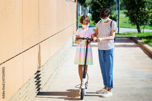 Mother teaching her daughter to ride an electric scooter