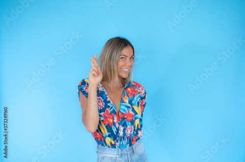 Pretty blond woman with okay gesture on blue background