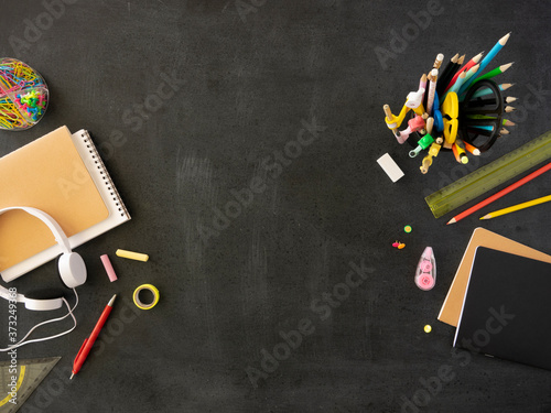 Back to school concept. Black chalkboard mockup with spiral notebook, headphones and stationery. Copy space for text or banner