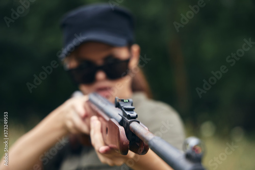 Woman on nature Woman with a gun in sunglasses sight green overalls 